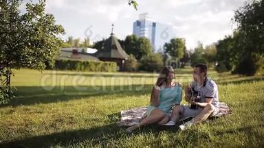 年轻漂亮的夫妇微笑着，在公园里休息。 弹吉他的人。